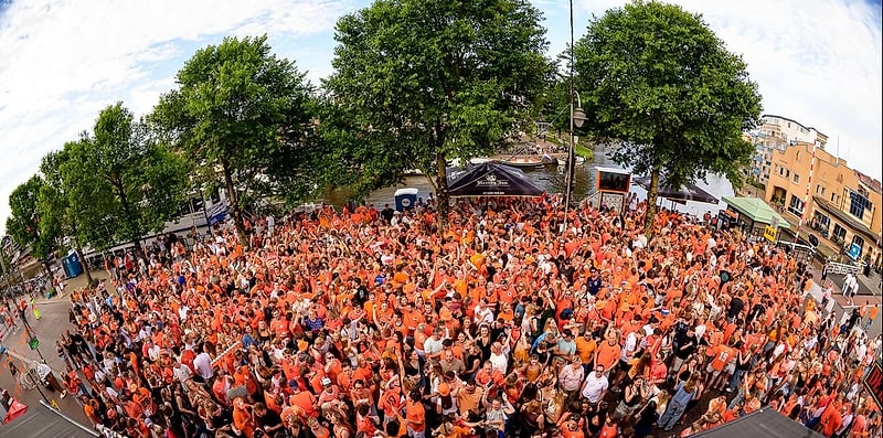 Oranje supporters op de kade bij De Kroon tijdens het WK '26, van bovenaf gezien